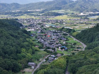 Aşağıdaki vadide küçük bir kasaba olan bir dağ manzarası. Kasaba ağaçlarla çevrili ve huzurlu bir atmosferi var.