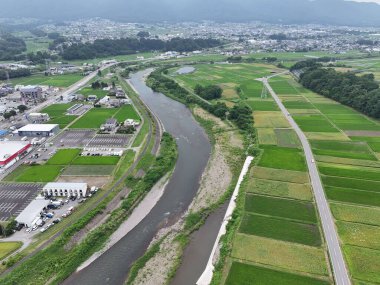 Bir nehir bir sürü yeşil arazisi olan bir kasabadan geçiyor. Nehir evler ve binalarla çevrili.
