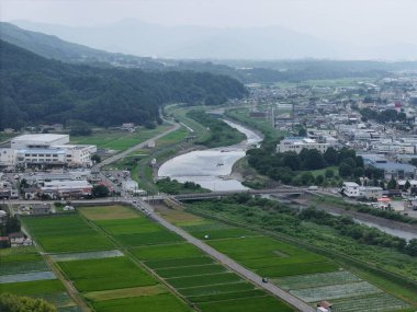 İçinden nehir akan bir şehir. Nehir yeşil tarlalarla çevrili ve şehir araba ve kamyonlarla dolu.