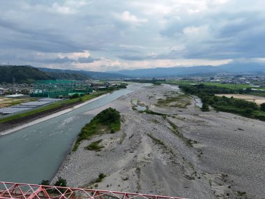 İçinde bir sürü taş ve toprak olan bir nehir. Su berrak ve gökyüzü bulutlu.