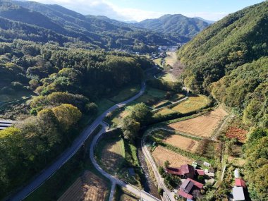 İçinden yol geçen bir dağ sırası. Yol ağaçlarla çevrili ve manzara çok sakin.