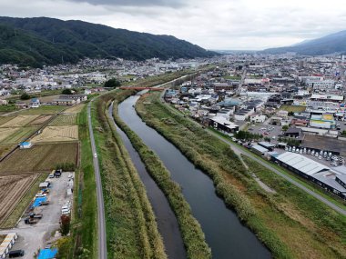 Bir nehir, üzerinde köprü olan bir şehrin içinden akar. Şehir araba ve binalarla dolu.