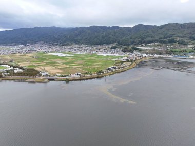 Bir şehir manzarası ve önünde köprüsü olan bir göl. Şehir büyük bir su kütlesiyle çevrilidir.