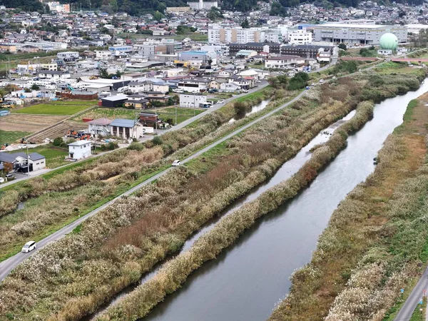 Kıyıları boyunca bir sürü ot ve otla dolu bir nehir. Nehir evler ve binalarla çevrili.