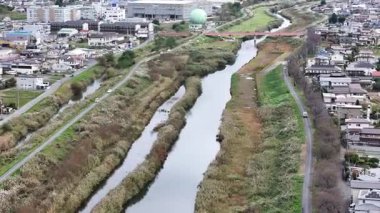 Nehrin yeşil arazide ve binalarda dalgalanan hava görüntüsü.