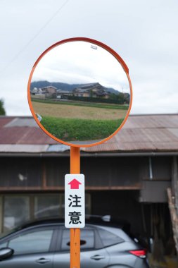 Yuvarlak turuncu bir tabela, üstünde ayna ve altında kırmızı ile 