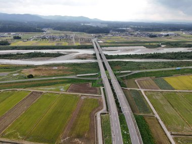 Büyük bir köprü kırsal bir alanda bir nehri kapsar. Köprü tarım arazileriyle çevrili ve nehri geçmenin tek yolu bu.