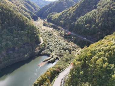 İçinden nehir akan bir dağ sırası. Nehir ağaçlarla çevrilidir ve dağlar yeşil yapraklarla kaplıdır. Sahne huzurlu ve sakin, suyla birlikte.