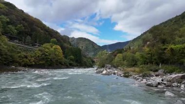 Yeşil dağlar ve bulutlu gökyüzü ile çevrili akan nehir.