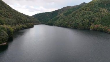 Sakin nehir bulutlu gökyüzünün altında yeşil dağlar arasında akıyor.