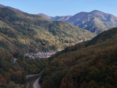 Vadide küçük bir kasabası olan bir dağ sırası. Kasaba ağaçlarla çevrili ve dağlar sonbahar yapraklarıyla kaplı.