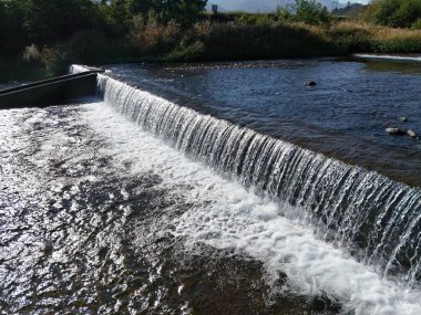 Bir su akıntısı tepeden aşağı akıyor. Su berrak ve sakin. Su kayaların ve çakıl taşlarının üzerinden akıyor.