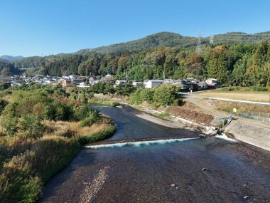 Üzerinde köprü olan bir nehir ve arka planda bir kasaba. Nehir kahverengi, köprü beyaz.