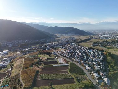 Bir sürü evi ve bir sürü yeşil arazisi olan bir şehir. Gökyüzü mavi ve güneş parlıyor.