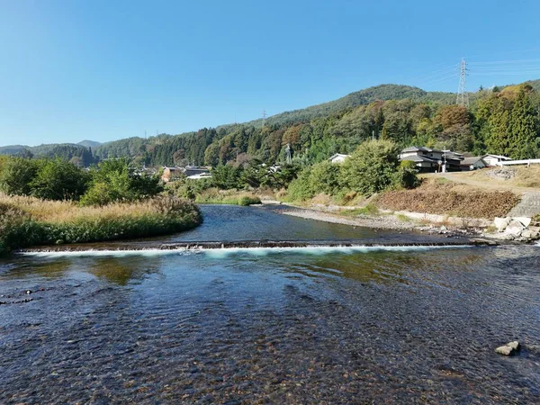 Üzerinde köprü olan bir nehir ve arka planda bir ev. Su sakin ve berrak.