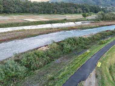 Her iki tarafında yeşil ve kahverengi orman olan bir nehir. Nehir geniş ve kenarında sarı bir tabela var.