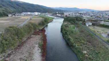 Yeşil arazi ve tarlalarda akan nehrin havadan görünüşü