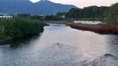 Yeşil arazi ve dağlarda akan sakin bir nehir.