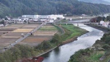Nehir tarlaların ve kırsal alandaki binaların yanında akıyor.