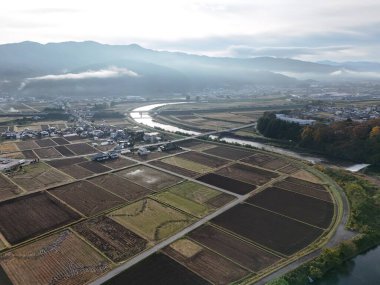 Kırsal bir bölge ve içinden bir nehir geçiyor. Gökyüzü bulutlu ve güneş parlamıyor.
