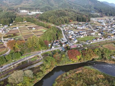 İçinden nehir akan bir kasaba. Evler dağılmış ve bir sürü ağaç var.