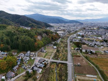 Köprüsü ve arka planda evleri olan bir şehir. Gökyüzü bulutlu ve şehir çok meşgul değil.