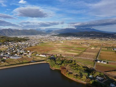 Arka planda göl olan güzel bir şehir manzarası. Gökyüzü açık ve güneş parlıyor.