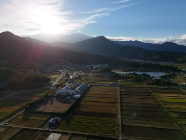 Ortasında küçük bir kasaba olan güzel bir manzara. Gökyüzü mavi ve güneş ışıl ışıl parlıyor