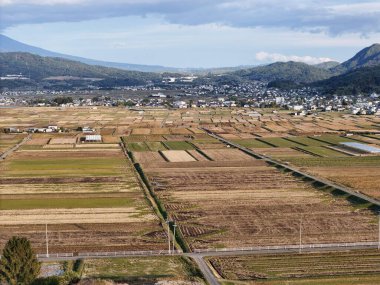 Arkasında bir şehir olan uçsuz bucaksız, boş bir ekin tarlası. Sahne sakin ve sakin, açık alan ve uzak şehir manzarası bir huzur hissi yaratıyor.