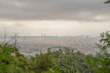 Bulutlu bir gökyüzü ve arka planda birkaç ağaç olan bir şehir manzarası. Şehir binalarla dolu ve gökyüzü bulutlu.