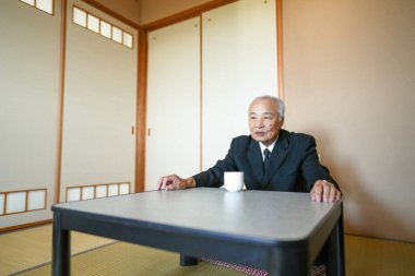 Yaşlı bir adam önünde bir fincan ile bir masada oturur. Sahne sessiz ve huzurlu, düşüncelere dalmış bir adam.