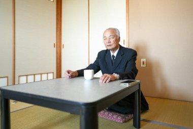 Takım elbiseli bir adam önünde bir fincanla masada oturur. Sahne sessiz ve huzurlu, düşüncelere dalmış bir adam.