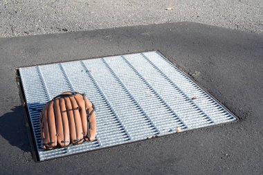 Sokakta bir beyzbol eldiveni ızgaranın üzerinde duruyor. Eldiven kahverengi ve üzerinde siyah bir logo var. Ortalık sakin ve sakin. Eldiveni bozacak kimse yok.