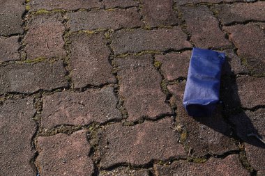 Mavi bir kulübe tuğla kaldırımda yatıyor. Kutu açık ve içindekiler görünür durumda. Olay yeri biraz dağınık ve dağınık.