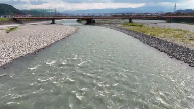 Köprünün altından akan nehir ve arka planda dağlar