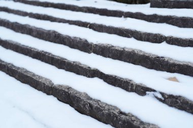 Karla kaplı bir merdiven. Merdivenlerde kar birikiyor, güzel ve huzurlu bir manzara yaratıyor. Beyaz kar, karanlık adımlarla çelişiyor. Merdivenleri daha da dramatik gösteriyor.