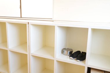 Ayakkabı dolu beyaz bir dolap. Bir çift siyah ayakkabı dışında raf boş.