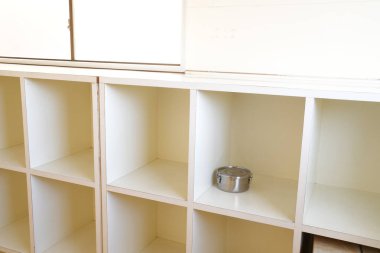 Üzerinde gümüş kase olan beyaz bir raf. Raflar boş.