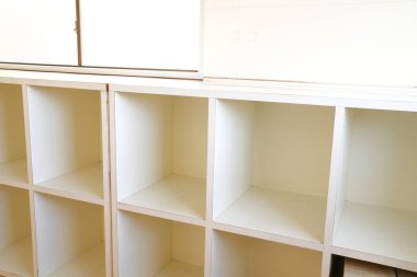 Boş rafları olan beyaz bir kitaplık. Raflar sıralı ve kitaplık uzun.