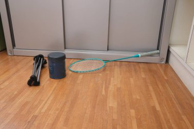 Bir tenis raketi ve mavi beyaz bir tenis topu ahşap bir zemine yerleştirilir.