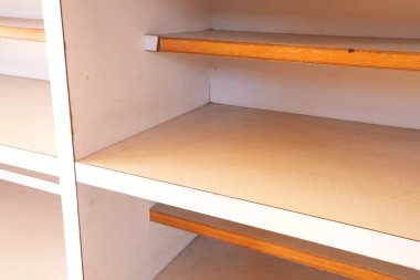 Altında ahşap bir raf olan beyaz bir raf. Rafta tahtadan yapılmış ve beyaz bir kaplama var.