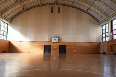 Bir basketbol sahası boş ve duvarlar ahşap kaplı. Saray geniş ve güneş pencerelerden içeri doğru parıldıyor.