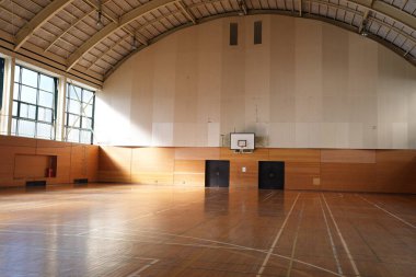 Bir basketbol sahası boş ve duvarlar beyaz. Saray geniş ve duvarlar ahşap kaplı.