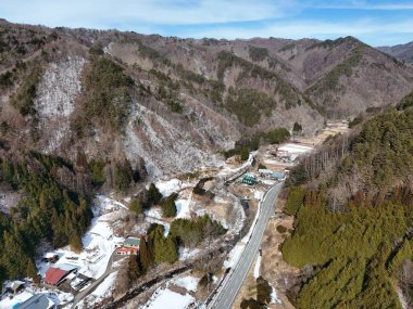 Aşağıdaki vadide küçük bir kasabası olan karlı bir dağ sırası. Kasaba ağaçlarla çevrili ve dağlar karla kaplı. Huzurlu ve huzurlu bir sahne.