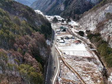 Birkaç evi ve arabası olan karlı bir dağ yolu. Yol boş ve evler küçük.