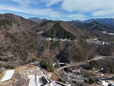 Önünde karlı bir yol olan bir dağ sırası. Dağlar karla kaplı ve yol dağın yamacını kaplıyor. Huzurlu ve huzurlu bir sahne.