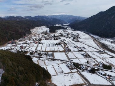 Ortasında küçük bir kasaba olan karlı bir manzara. Kasaba karla çevrili ve sakin bir atmosferi var.