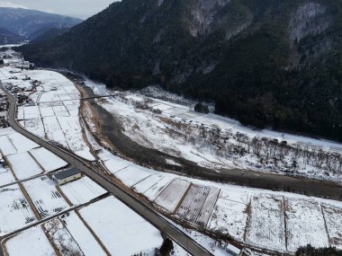İçinden bir nehir akan karlı bir manzara. Kar zemini kaplıyor ve nehir dondu. Huzurlu ve huzurlu bir sahne.