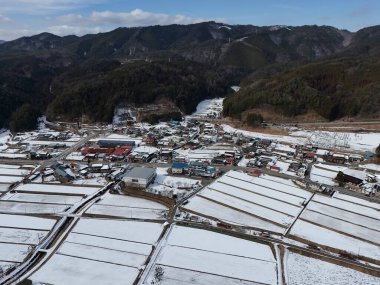 Ortasında küçük bir kasaba olan karlı bir manzara. Kasaba karla çevrili ve sakin bir atmosferi var.