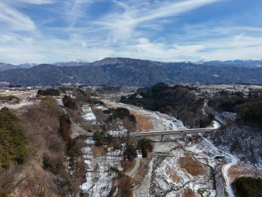 Ortasında köprü olan karlı bir dağ sırası. Köprü ağaçlar ve karla çevrili.